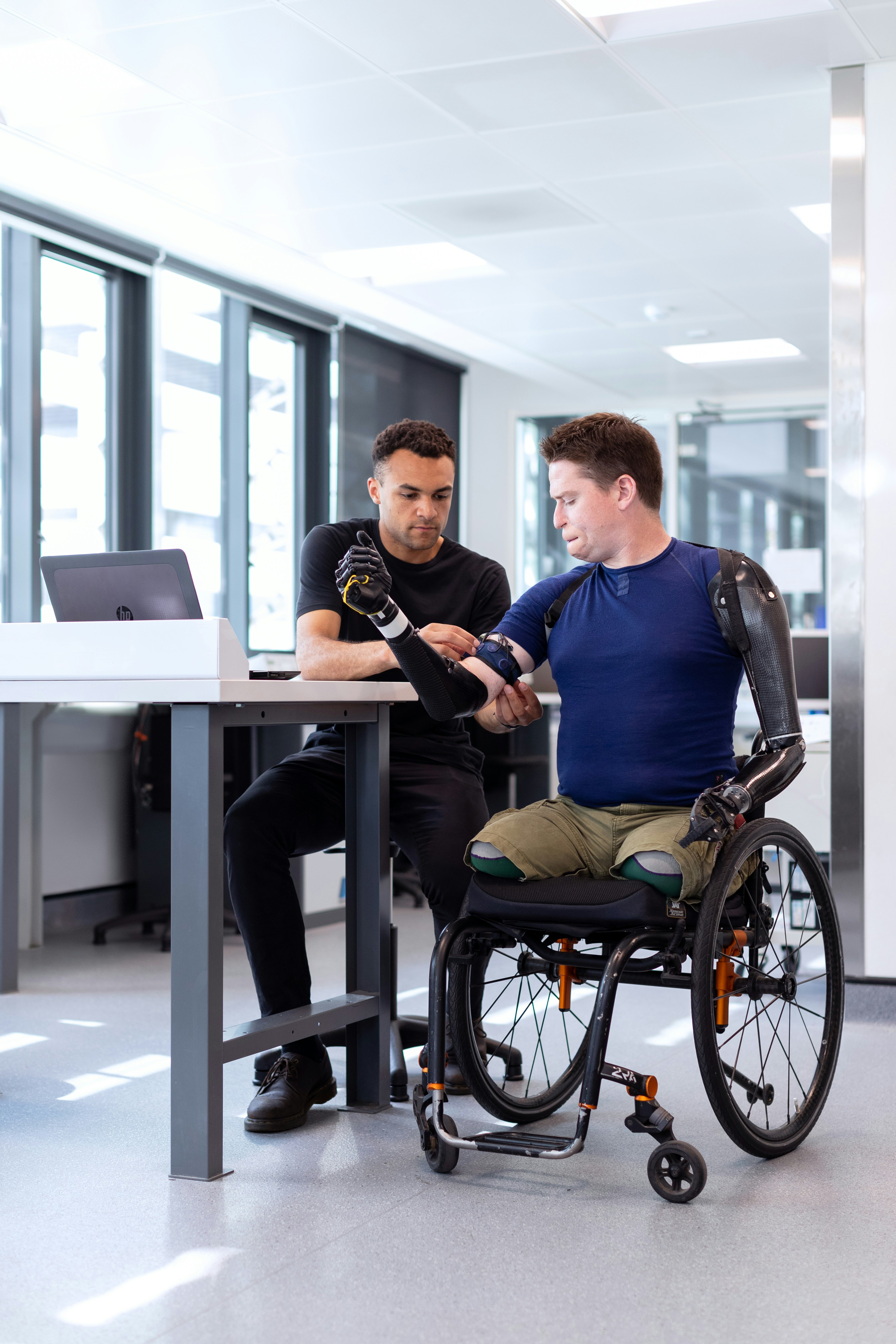 Support staff working with an individual using a prosthetic arm, demonstrating care and collaboration